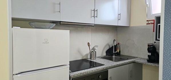 Et køkken med køleskab, vask og kaffemaskine.