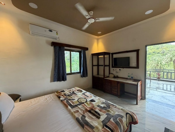 A bedroom with a bed, a desk, a chair, a ceiling fan, a window with curtains, and a balcony with a view of greenery. - Abu Hill villa (Aburaj)