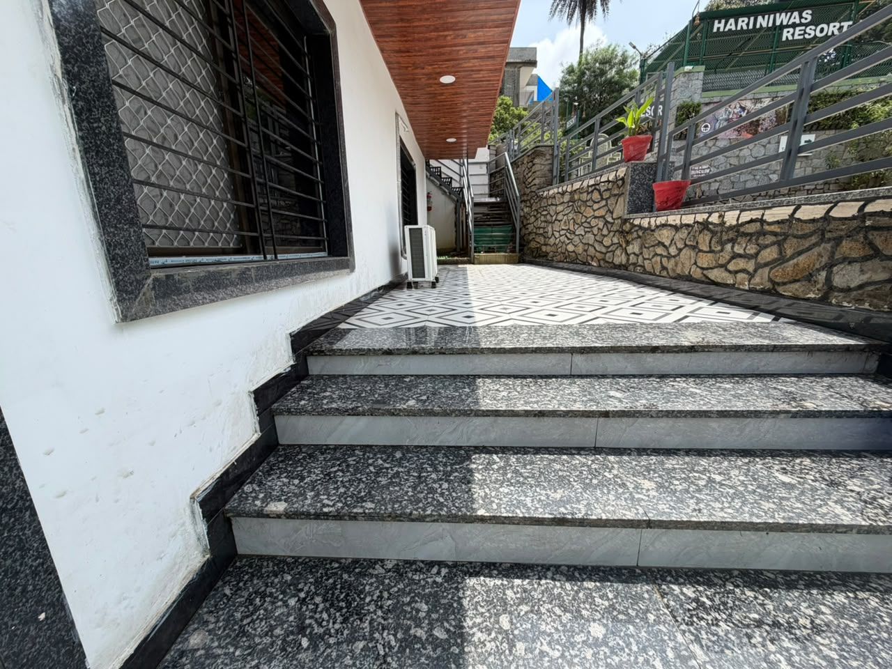 Una serie de escalones exteriores que conducen a un edificio de fachada blanca y pared de piedra.