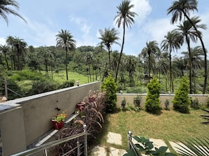 A balcony with a view of a tropical landscape, including palm trees and a grassy area. - Abu Hill villa (Aburaj)