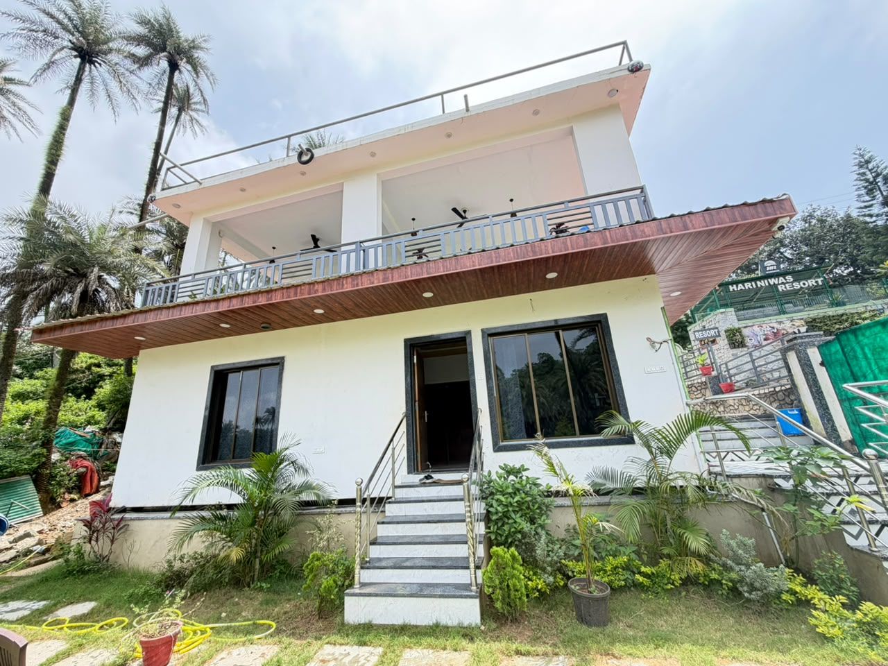 A two-story building with a balcony, a staircase leading to the entrance, and a sign indicating it is a resort.