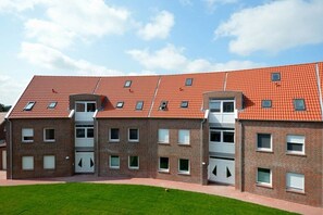 A multi-story building with a red-tiled roof, brick exterior, and multiple windows. - Holiday apartment with 2 bedrooms (Norddeich)