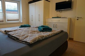 A bedroom with a bed, a wardrobe, a television, and a window. - Holiday apartment with 2 bedrooms (Norddeich)