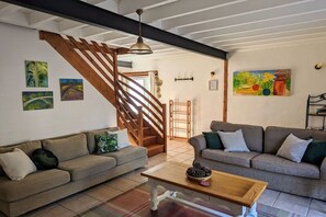 A living room with two sofas, a coffee table, and a staircase. - Holiday home in Vesly with swimming pool (Vesly)