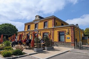 A yellow building with outdoor seating and a clock on the facade. - Holiday home in Vesly with swimming pool (Vesly)