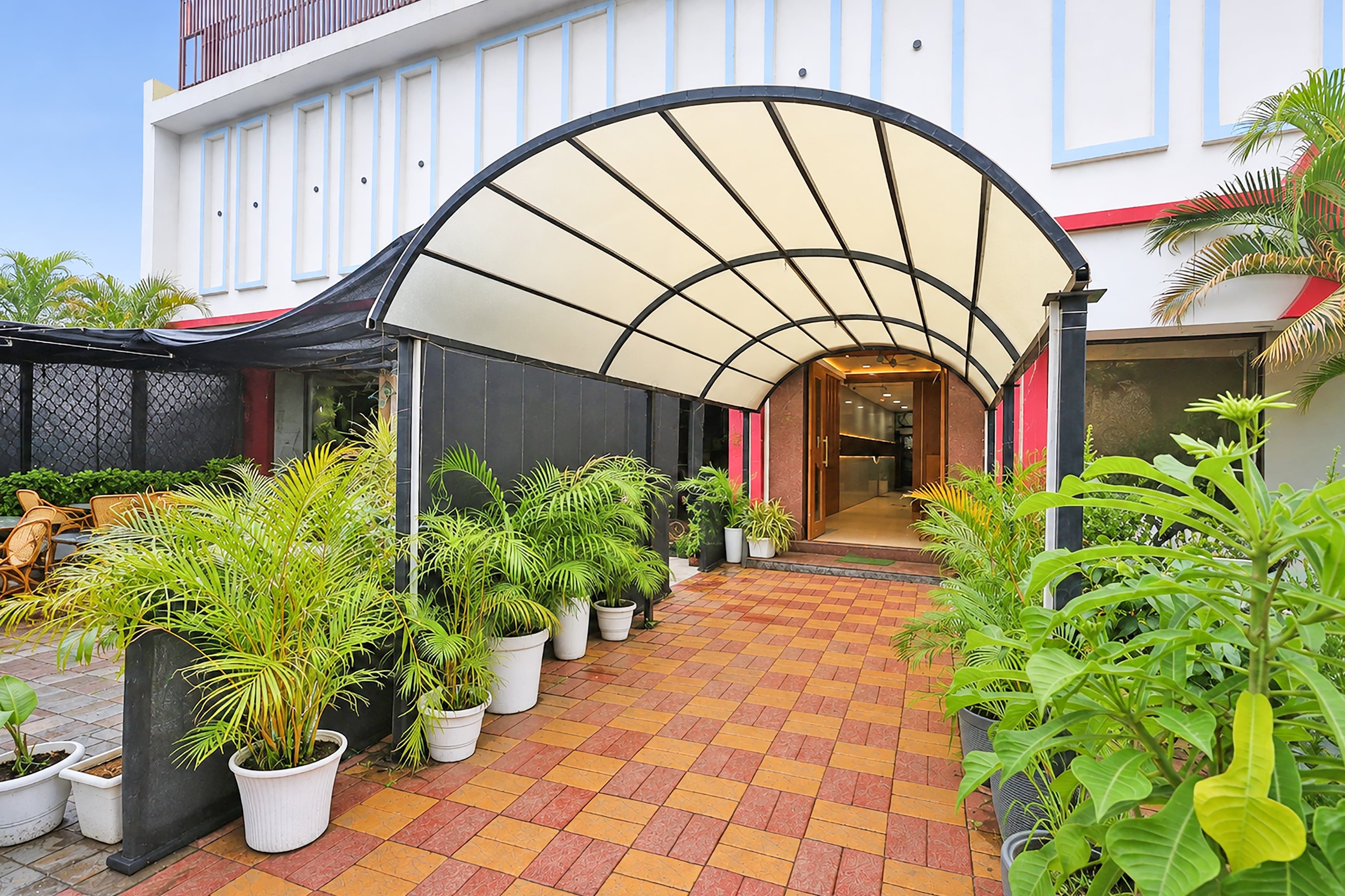 Un pasillo cubierto con plantas en macetas, que conduce a la entrada de un edificio.