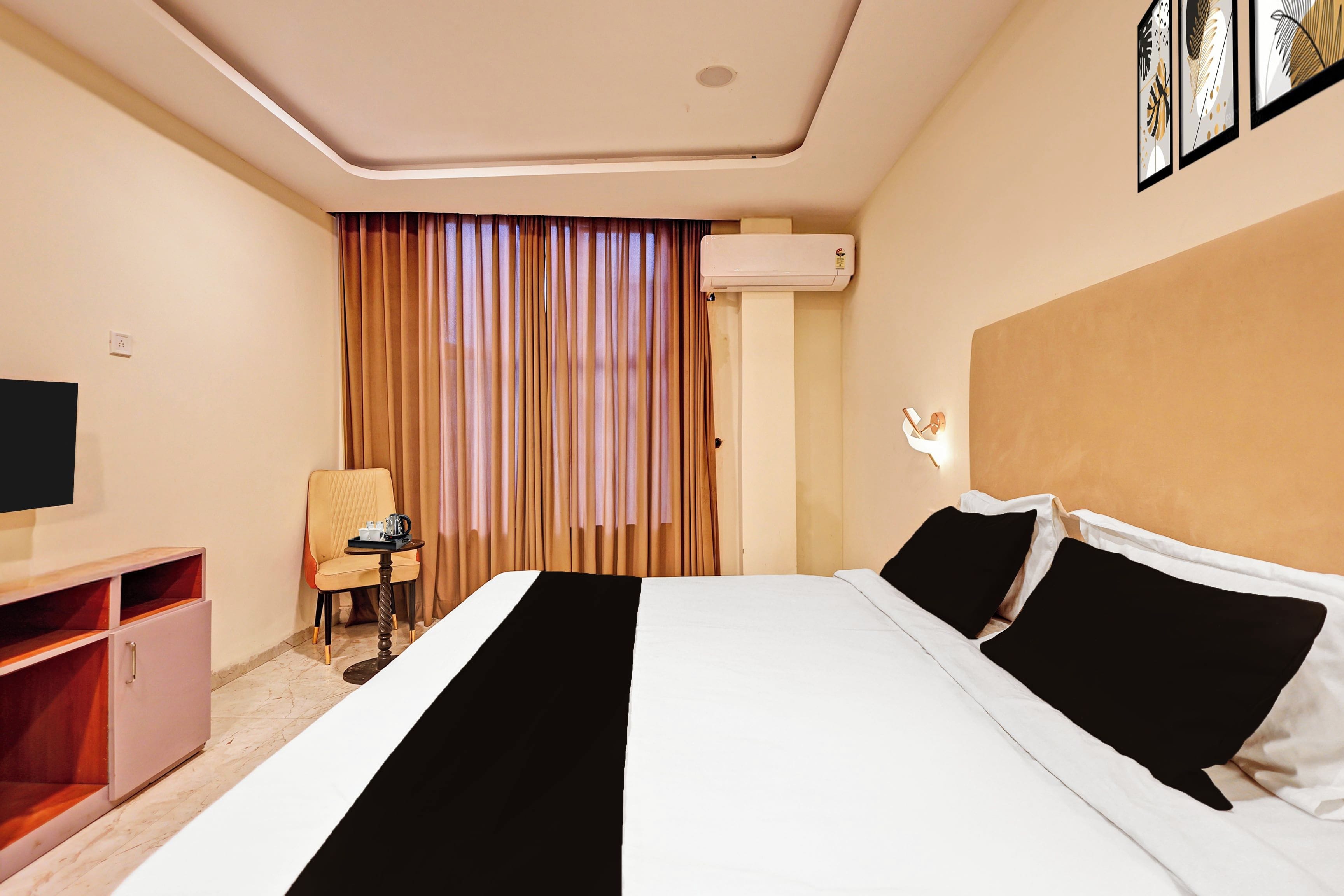 Habitación de hotel con cama, una silla, escritorio, unidad de aire acondicionado y televisor montado en la pared.