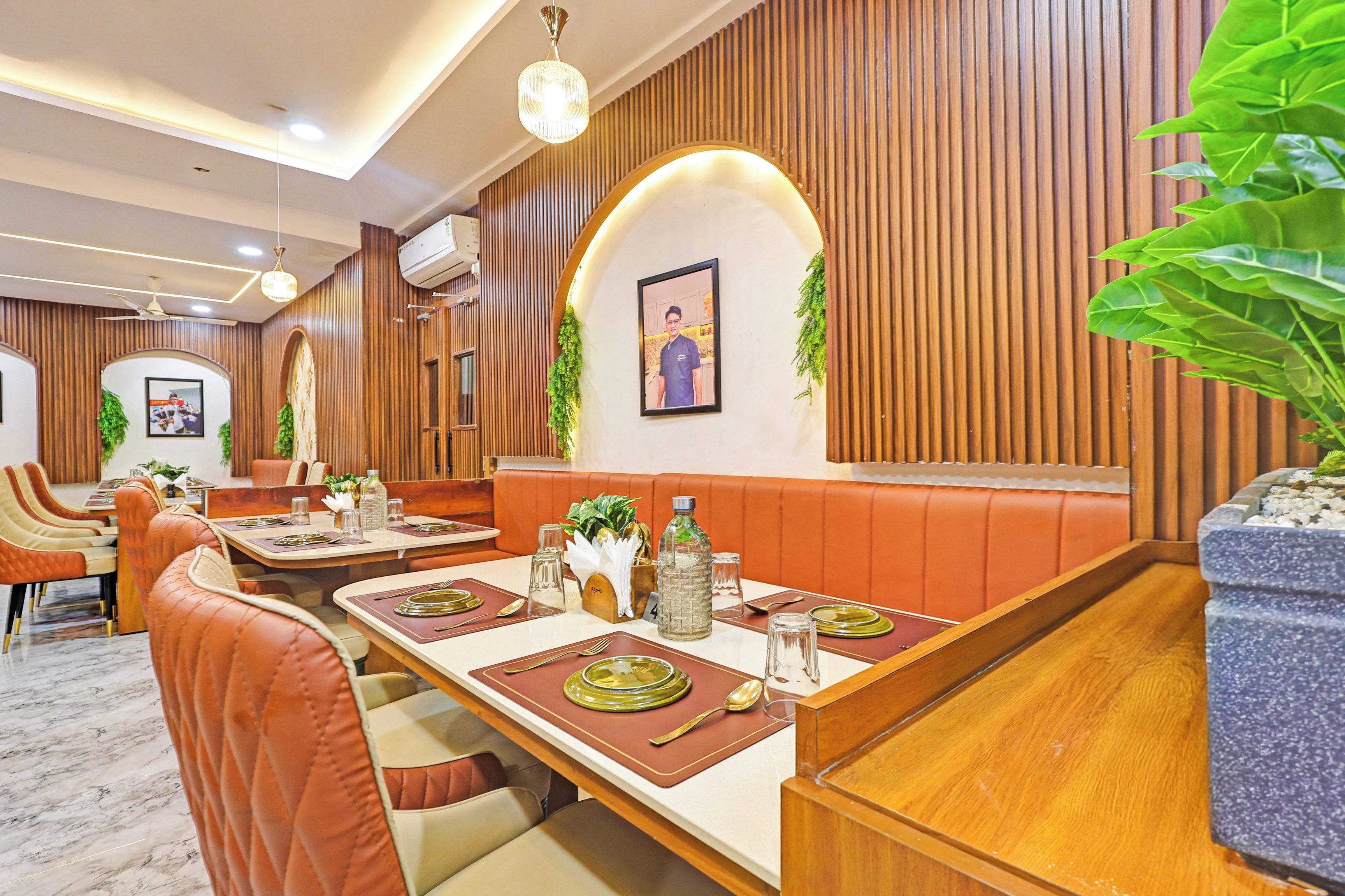 A restaurant with booths, tables set with cutlery, and a ceiling fan.