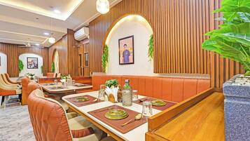 A restaurant with booths, tables set with cutlery, and a ceiling fan.