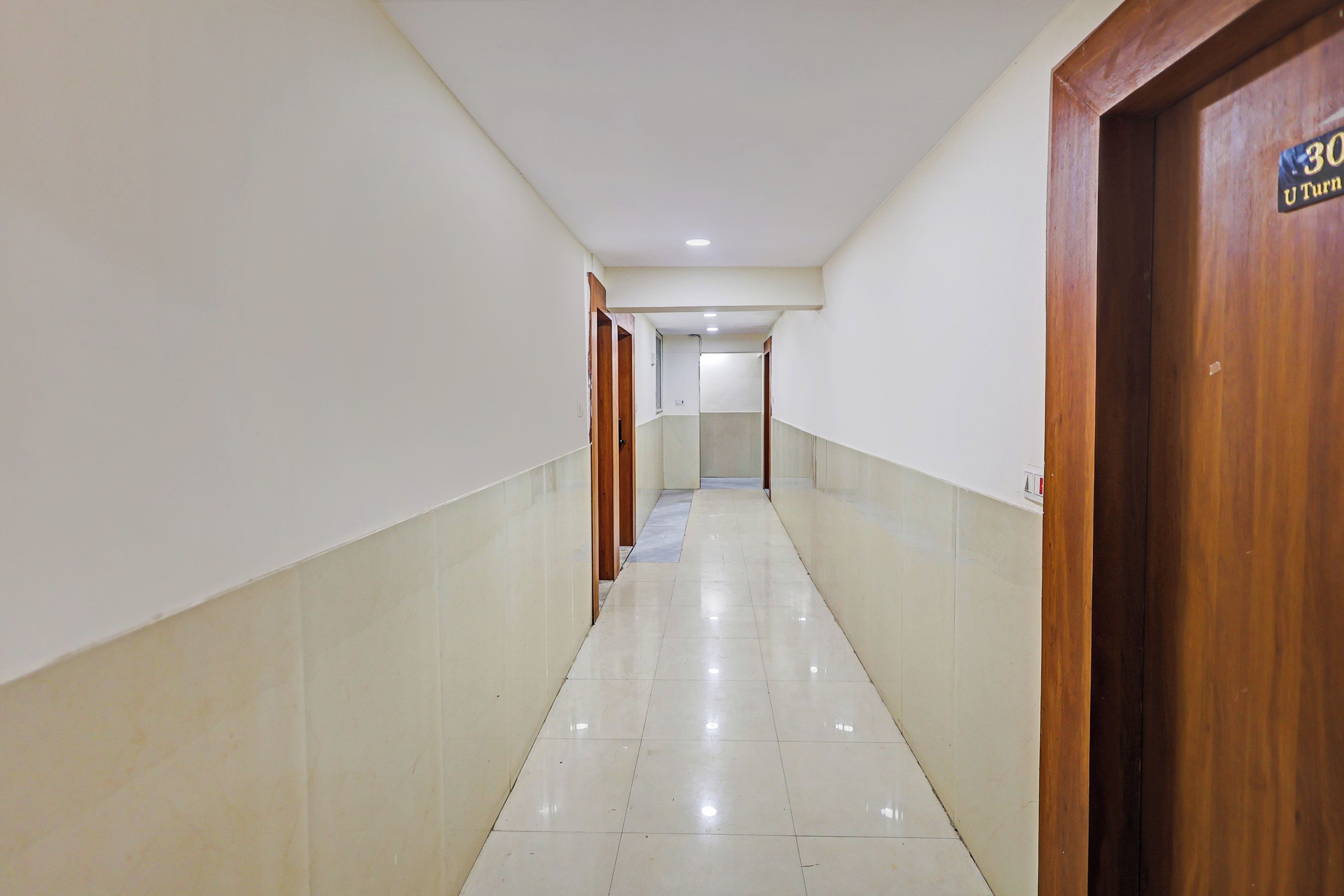 A corridor with a wooden door on the right, a sign reading '30 U Turn', and a tiled floor.
