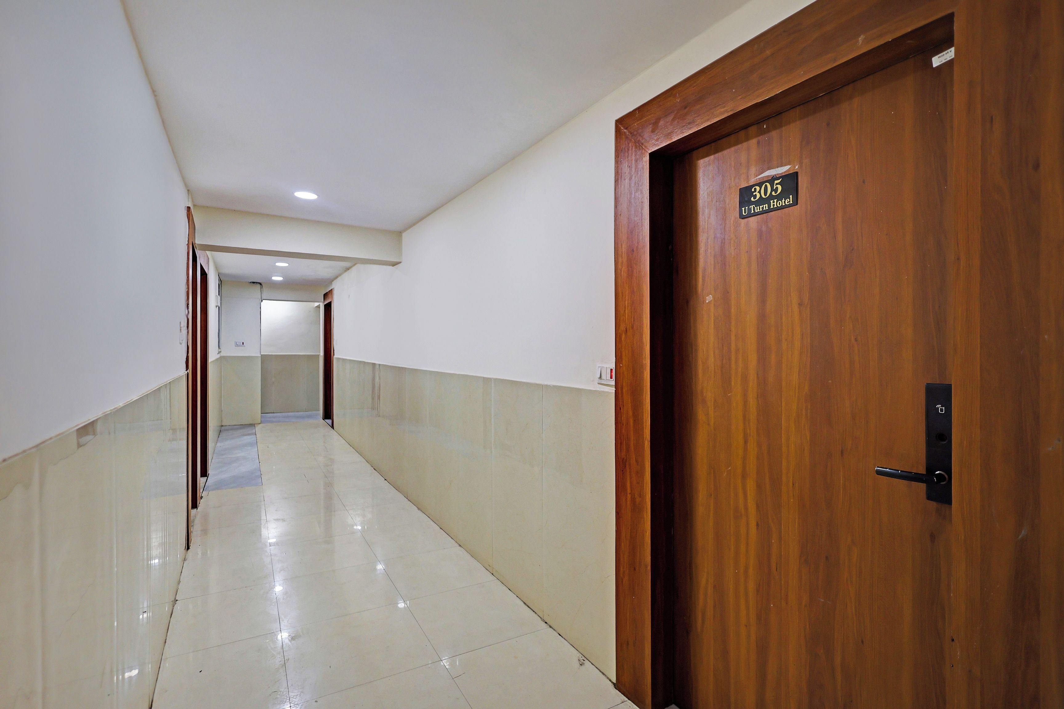 Un pasillo de hotel con una puerta de madera que indica '305 U Turn Hotel' y un piso de baldosas.