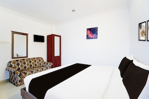 A hotel room with a bed, a sofa, a television, and a door. - Collection  Formerly Malabar Residency (Kanayannur)