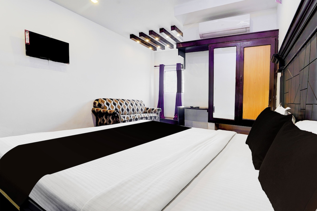 Una habitación de hotel con cama, sofá, televisión y armario.
