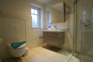 A modern bathroom with a toilet, sink, and shower. - Holiday apartment with 2 bedrooms (Norddeich)