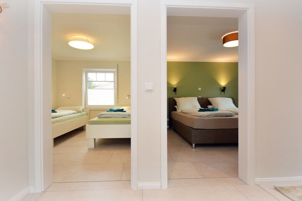 A room with a bed, a window, and a door leading to another room.