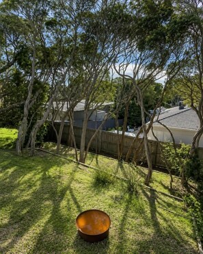 A backyard with trees, a fence, and a metal bowl. - Best of Both Beaches in Blairgowrie (Mornington Peninsula Shire)