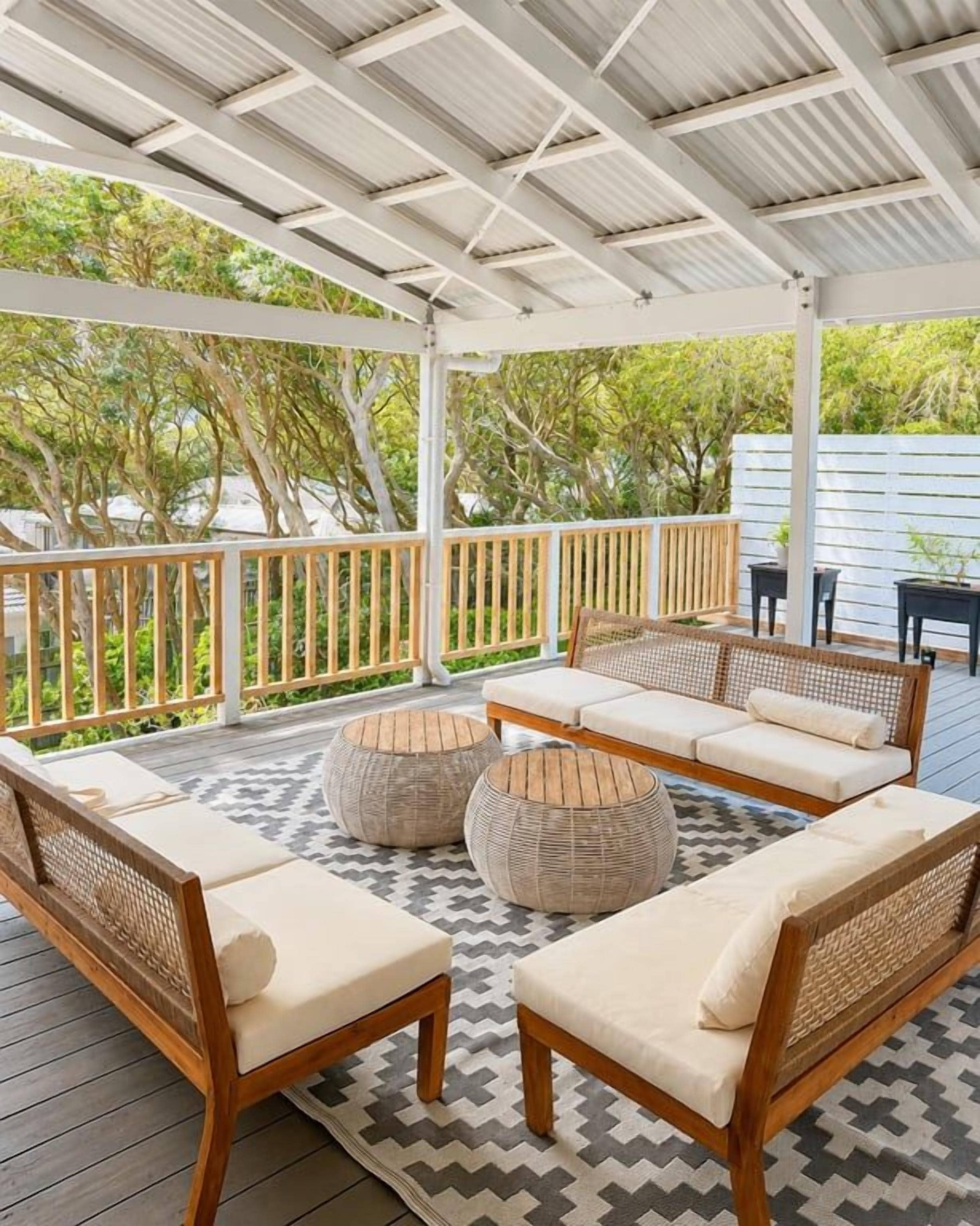 A covered outdoor seating area with wicker furniture and a patterned floor.