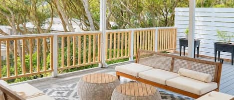 A covered outdoor seating area with wicker furniture and a patterned floor.
