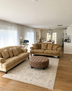 A living room with two sofas and a coffee table, a dining area with a chandelier, and a kitchen in the background. - Best of Both Beaches in Blairgowrie (Mornington Peninsula Shire)