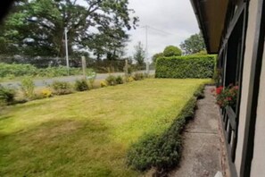 A well-maintained lawn with a hedge and a pathway leading to a building. - Gite - Les Ravalieres (Livre-la-Touche)