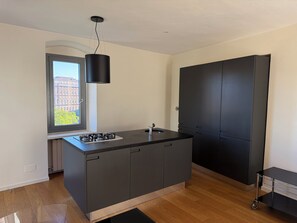 Ett modernt kök med en inbyggd gasspis, ett fönster med utsikt över byggnader och ett svart skåp.