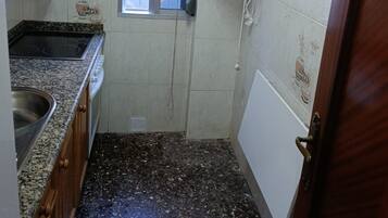 Una cocina compacta con ventana, calentador de agua y una puerta.