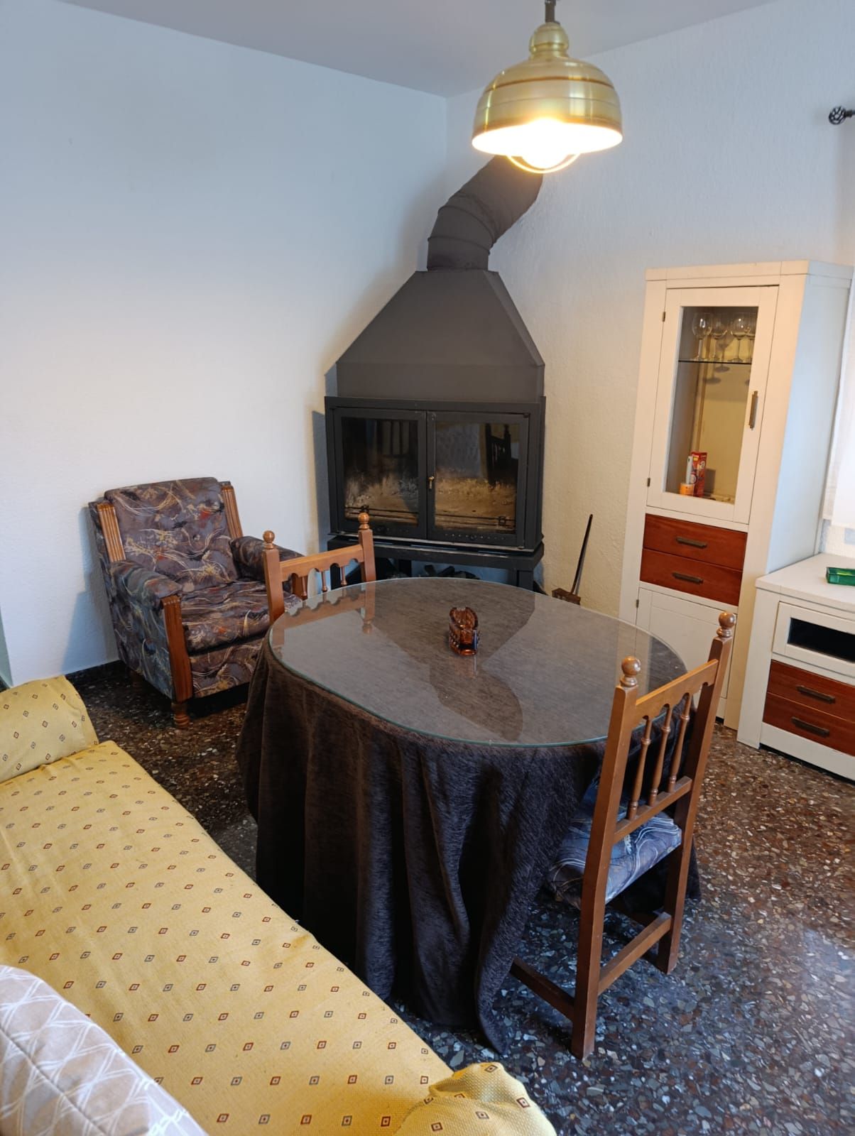 Una habitación acogedora con una mesa redonda, sillas, un sofá, chimenea y un armario.