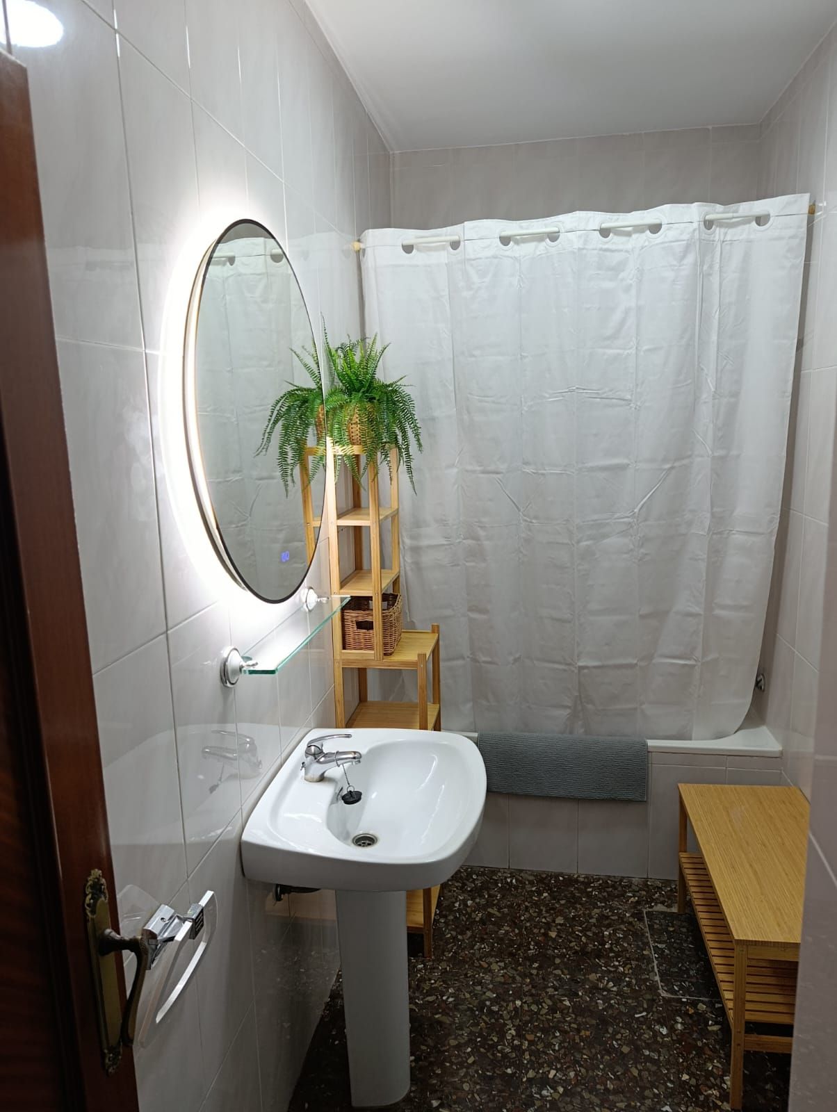Un baño con lavabo blanco, espejo y cortina de ducha.