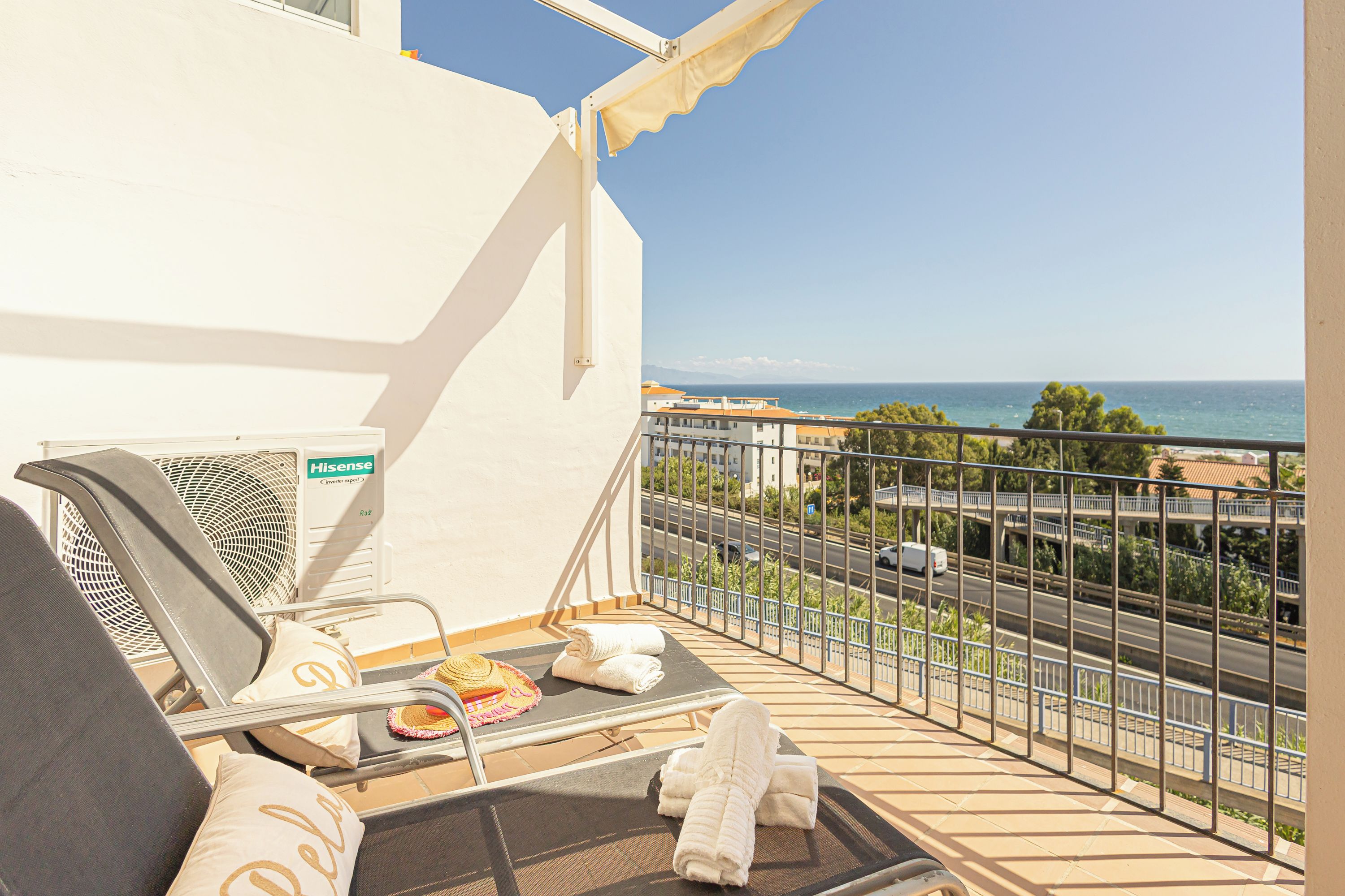 Un balcón con zona de estar, un Hisense inverter y vistas al mar y al paisaje urbano.