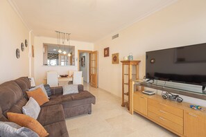 Una sala de estar con sofá, televisor y mueble de madera con cajones.