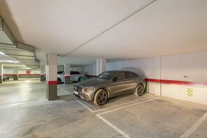 Un garaje de estacionamiento con un coche gris aparcado en un espacio reservado.