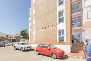 Un edificio con un letrero que dice 'MANILVA PLAZA' y un estacionamiento con varios autos.