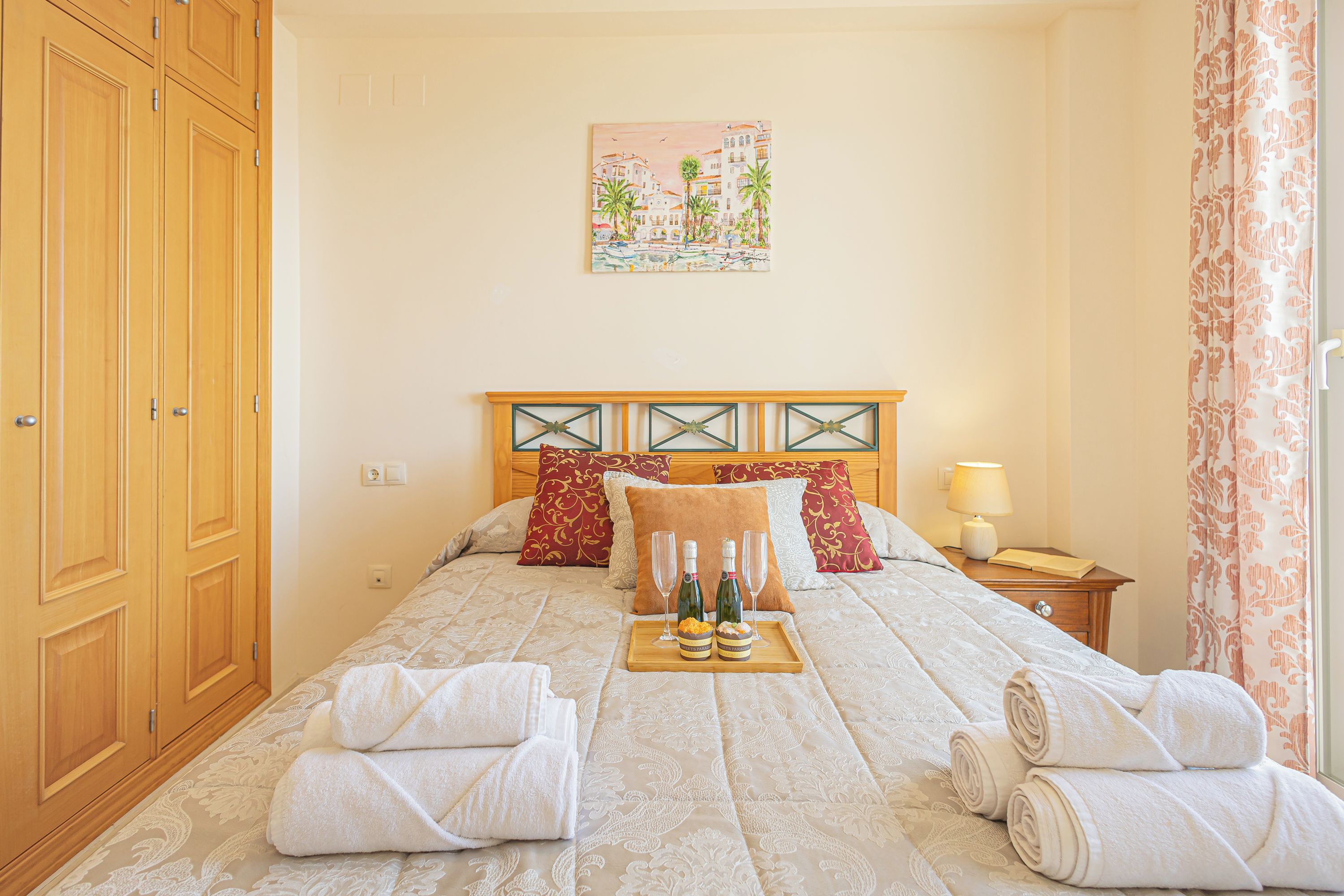 A hotel room with a bed, a nightstand, a painting, and a wardrobe.