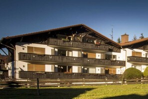Ein mehrstöckiges Gebäude mit Balkonen, einer Holzfassade und blauem Himmel.