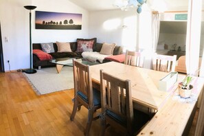 Ein gemütliches Wohnzimmer mit einem Holzesstisch, einer Couch mit Kissen und einem Bild an der Wand.