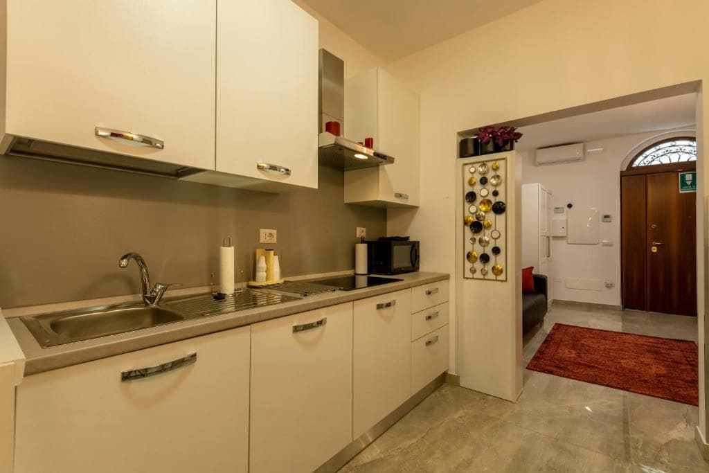 Una cocina con lavamanos, armarios, microondas y un adorno de pared.