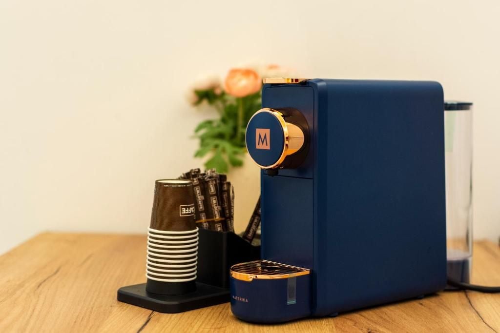 Eine Kaffeemaschine mit blauer Oberfläche und goldenem Akzent, auf einem Holztisch platziert.