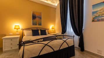 A bedroom with a bed, two bedside tables, a painting on the wall, and a window with curtains.