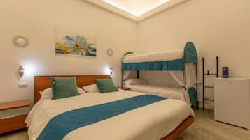 Een hotelkamer met een stapelbed, een nachtkastje, een lamp, een kunstwerk aan de muur en een kleine koelkast.