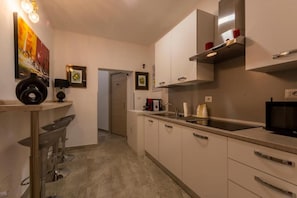 A modern kitchen with white cabinets, a black microwave, and a stainless steel range hood. - Urban Beach Sirena (Francavilla al Mare)