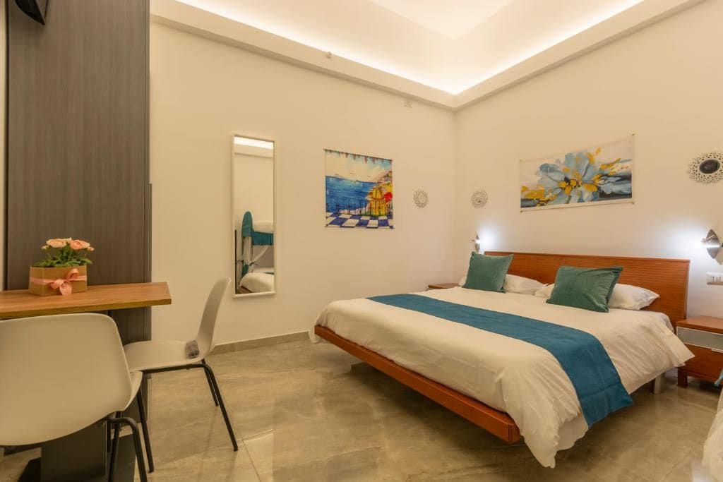 A bedroom with a bed, bedside tables, a desk, and chairs.