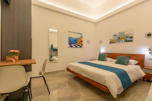 Un dormitorio con cama, mesitas de noche, escritorio y sillas.