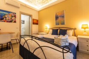 A hotel room with a bed, bedside tables, a desk, and chairs.