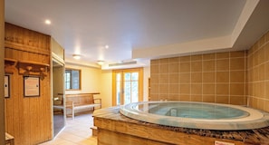 Ein Wellnessbereich mit Whirlpool, Holzliegen und einer gefliesten Wand.