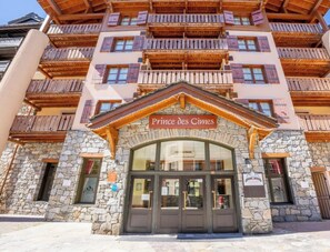 Ein Hotelzugang mit einer Steinfassade, hölzernen Balkonen und einem Schild mit der Aufschrift 'Prince des Cimes'.