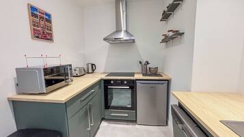 A compact kitchen with a built-in oven, a microwave, a toaster, and a stainless steel range hood.
