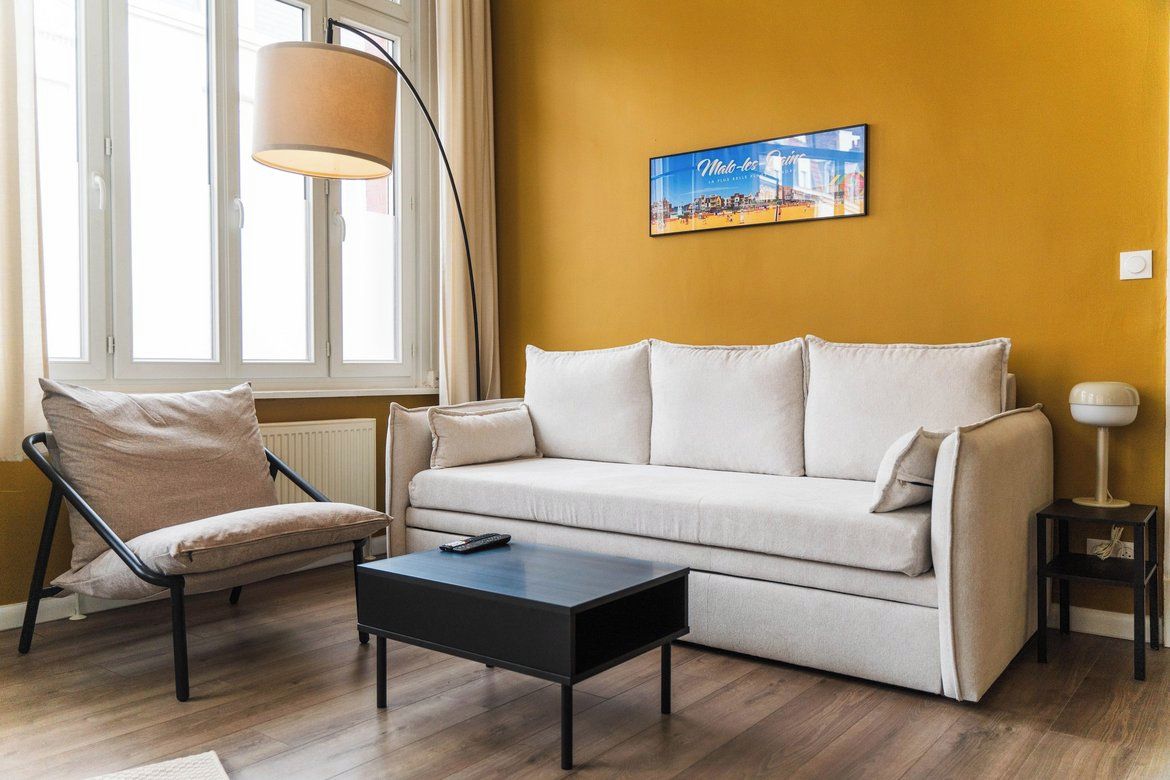 Ein Wohnzimmer mit einer Couch, einem Sessel, einem Couchtisch, einer Lampe und einem Bild an der Wand.