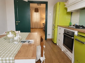 A kitchen with a wooden table, a green refrigerator, and a stove. - A villa for exclusive use, in the countryside, secluded yet close to major cities (Toscana)