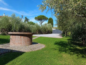 A garden with a brick structure, a paved path, and a large tree. - A villa for exclusive use, in the countryside, secluded yet close to major cities (Toscana)