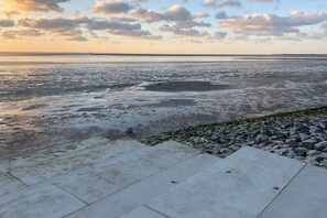 Un chemin en béton qui mène à une côte rocheuse, d’où l’on peut admirer la mer et le ciel.
